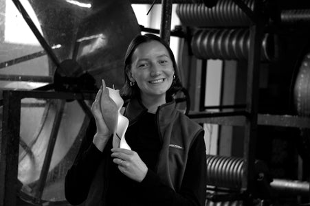 Schwarzweiß Foto von Pia Zengerle in der Werkstatt mit zwei Engelskerzen in der Hand